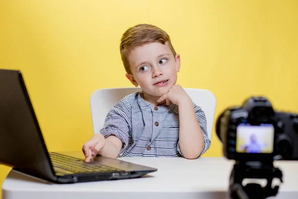 Kid blogger filming video on camera working with the laptop, at home. Online learning. Online school