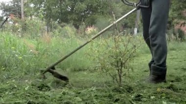 Elektrikli çim biçme makinesiyle çim biçen bir işçi. Bahçıvanlık malzemeleri ve ekipmanlar. Çim biçme makinesiyle çim biçme işlemi.