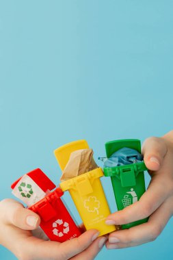 Sarı, yeşil ve kırmızı geri dönüşüm kutularında mavi arka planda geri dönüşüm sembolü var. Şehri düzenli tutar, geri dönüşüm sembolünü bırakır. Doğa koruma kavramı.