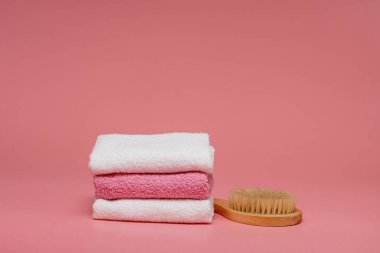 Anti-selülit masajı için vücut fırçası ve pembe arka planda yumuşak havlularla cilt tedavisi. Tasarımı kopyalama alanı ile düzenleyin. Spa konsepti