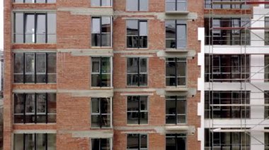 Yeni bir apartman bloğunda çalışma platformları sağlayan geniş yapı iskelesi, inşaat halindeki uzun bina.
