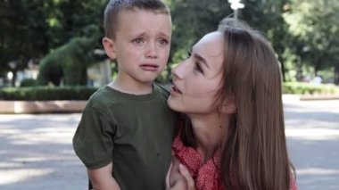 Küçük çocuk dışarıda acı acı ağlıyor. Annem ağlayan bir çocuğu rahatlatıyor.
