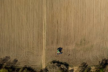 Havadan bakıldığında büyük bir traktör kuru bir alan oluşturuyor. Yukarıdan aşağıya traktör, toprağı işliyor ve kuru bir tarla ekiyor. Hava traktörü, tarla ekimi için çayırları kesiyor.