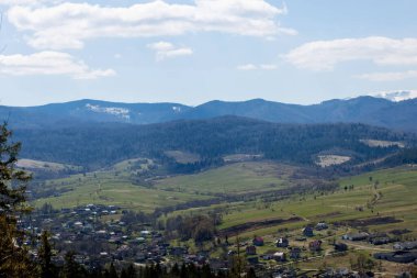 Bulutlu bir yaz gününde Karpat Dağları manzarası. Dağ zirveleri, ormanlar, tarlalar ve çayırlar, güzel doğal manzara..
