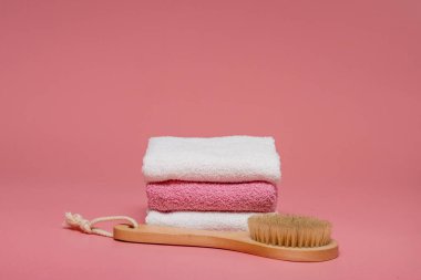 Anti-selülit masajı için vücut fırçası ve pembe arka planda yumuşak havlularla cilt tedavisi. Tasarımı kopyalama alanı ile düzenleyin. Spa konsepti