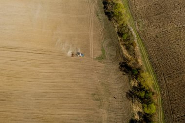 Havadan bakıldığında büyük bir traktör kuru bir alan oluşturuyor. Yukarıdan aşağıya traktör, toprağı işliyor ve kuru bir tarla ekiyor. Hava traktörü, tarla ekimi için çayırları kesiyor.