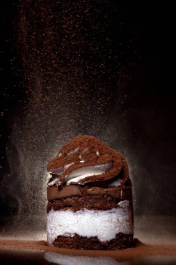 Tezgahın üzerine koyu arkaplan kakao serpilmiş taze pişmiş çikolatalı pastanın yan görüntüsü. Alçakgönüllülük. Kış yiyeceği ve içecek konsepti. Seçici odak.