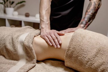 Genç bir kadın karın masajı yaptırıyor. Masör mide masajı yapar..