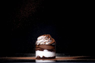 Tezgahın üzerine koyu arkaplan kakao serpilmiş taze pişmiş çikolatalı pastanın yan görüntüsü. Alçakgönüllülük. Kış yiyeceği ve içecek konsepti. Seçici odak.