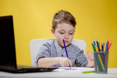 Uzaktan öğrenme çevrimiçi eğitim. Evde oturan ve ev ödevi yapan bir çocuk, karantinaya alınmış evde öğrenim görüyor.