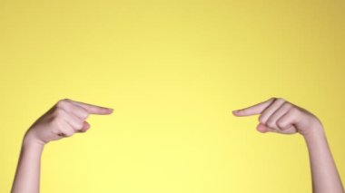Kadın elleri pastel sarı arkaplan üzerinde telif boşluğunu işaret ediyor. Reklam için kopyalama alanı. Metin veya resim için yer, promosyon içeriği. Reklam alanı, çalışma alanı maketi