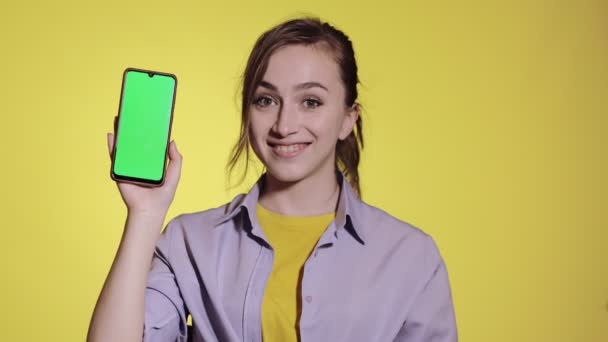 迷人的年轻女子指着智能手机上的绿色屏幕 — 图库视频影像