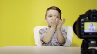 Çocuk blogcu, evde dizüstü bilgisayarla çalışırken kameraya video kaydediyor. Çevrimiçi öğrenme. Çevrimiçi okul