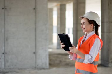 İnşaat alanında çalışan mühendis ya da mimar konsepti. İnşaat alanında tabletli bir kadın. Mimarlık Bürosu