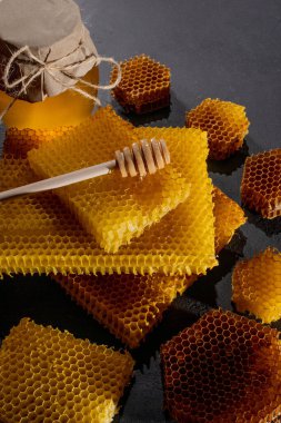 Bal geçmişi. Doğal bal tarağı ve tahta kaşık. Siyah kırsal masada.