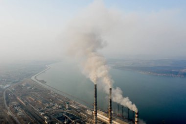 Kömür santralinden gelen gri dumanlı yüksek baca borularının havadan görüntüsü. Fosil yakıtla elektrik üretimi