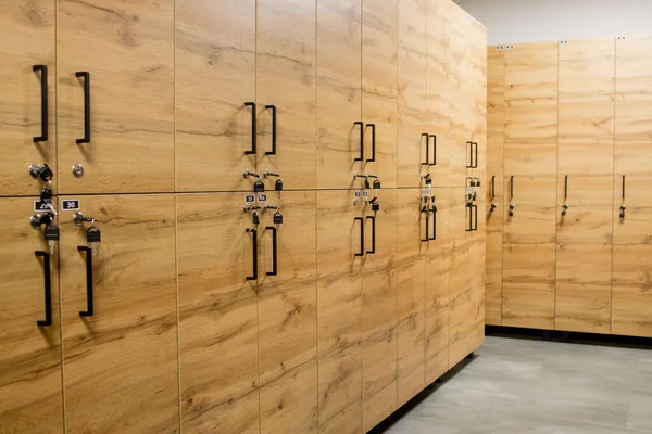 Wooden locker boxes, with metal locks. Classic wood locker room and a bench.