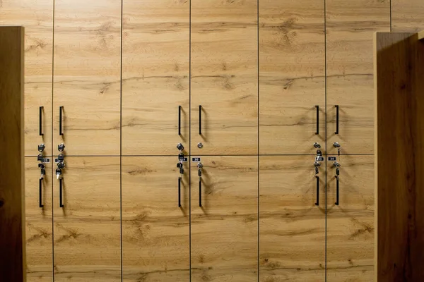 Wooden locker boxes, with metal locks. Classic wood locker room and a bench.