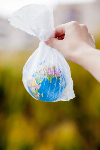 The human hand holds the planet earth in a plastic bag. The concept of pollution by plastic debris. Global warming due to greenhouse effect