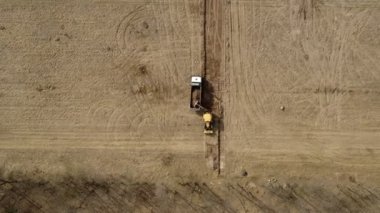 Yükleyici kazıcı zemini yol inşaatındaki kamyona yüklüyor..
