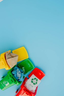 Sarı, yeşil ve kırmızı geri dönüşüm kutularında mavi arka planda geri dönüşüm sembolü var. Şehri düzenli tutar, geri dönüşüm sembolünü bırakır. Doğa koruma kavramı.
