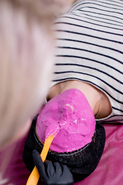 Alginaatmasker aanvraagproces. Een vrouwelijke handen van een schoonheidsspecialiste die spatels vasthoudt. De procedure voor huidverzorging in de schoonheidssalon. vrouw liggend op een bank in het kantoor van een schoonheidsspecialiste — Stockfoto