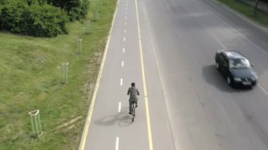 Şehir yolunda bisiklet sürme, şehir caddesinde yol işaretinin yanında bisiklet süren tanınmayan bir bisikletlinin gölgesi. Sağlıklı bisiklet yaşam tarzı.