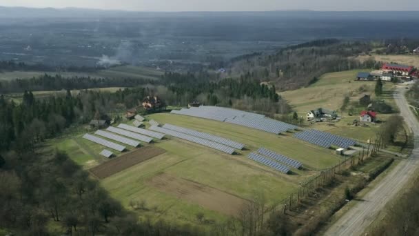 晴れた日にグリーンフィールドの太陽光発電所 空中展望 太陽光パネルは 発電のためのフィールドの行に立っています ドローンはソーラーファームの上を飛ぶ 再生可能エネルギー 代替エネルギー源 — ストック動画