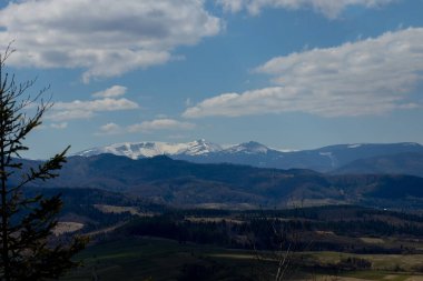 Bulutlu bir yaz gününde Karpat Dağları manzarası. Dağ zirveleri, ormanlar, tarlalar ve çayırlar, güzel doğal manzara..