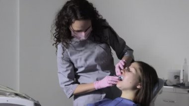 Kadın dişlerinde diş izi tepsisi kullanan ortodontist. Diş implantı için parmak izli diş spatulası..