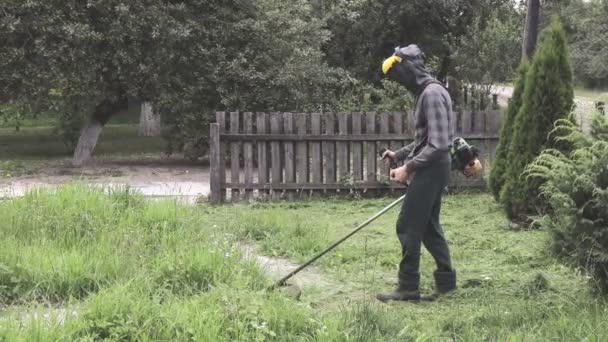 Falciatura operaia erba alta con tagliaerba elettrico o benzina. Attrezzi e attrezzature per la cura del giardino. Processo di potatura del prato con falciatrice manuale — Video Stock