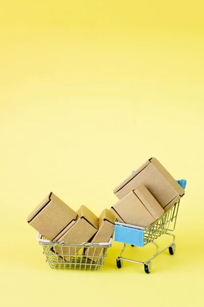 Sacos de compras de papel em um carrinho de compras em fundo amarelo, conceito de compras online. — Fotografia de Stock