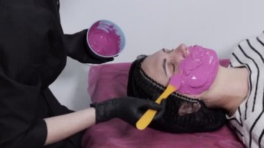 Maske uygulama sürecini değiştir. Spatula tutan bir güzellik uzmanının dişi elleri. Güzellik salonunda cilt bakımı prosedürü. Bir güzellik uzmanının ofisinde kanepede uzanmış bir kadın..