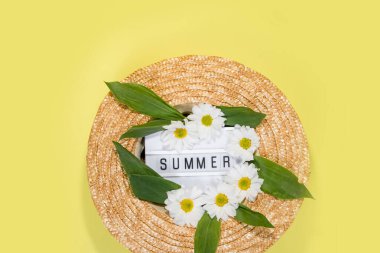Sarı arkaplan manzaralı yaz hasır şapkası düz fotokopi alanı uzanıyor. Yaz tatili konsepti, tek parça. Harflerden ve tarla papatyalarından sarı arkaplandaki çiçekleri yaz.