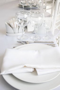 Yukarıdan beyaz masa ayarları. Zarif boş tabak, çatal bıçak, peçete ve cam..