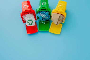 Sarı, yeşil ve kırmızı geri dönüşüm kutularında mavi arka planda geri dönüşüm sembolü var. Şehri düzenli tutar, geri dönüşüm sembolünü bırakır. Doğa koruma kavramı.