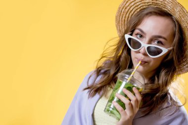 Yaz içeceği. Soğuk içecek. Güneş gözlüklü, elinde plastik mojito bardağı tutan mutlu bir kadın. Alkolsüz içki. Detox limonata.