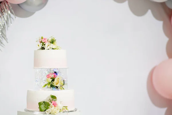 Tiered cake for wedding or birthday. Beautiful white and pink festive cake decorated with flowers.