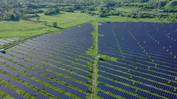 晴れた日に川の近くのグリーンフィールドの太陽光発電所の空中ビュー 太陽農場を飛び越える 太陽光パネルは生産のために列に立っています 再生可能エネルギー 代替エネルギー源 — ストック動画