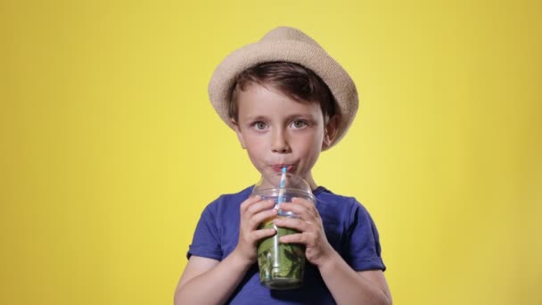 黄色のスタジオを背景にしたプラスチック製のカップからモヒートカクテルを飲むかわいい男の子 ビーチ — ストック動画