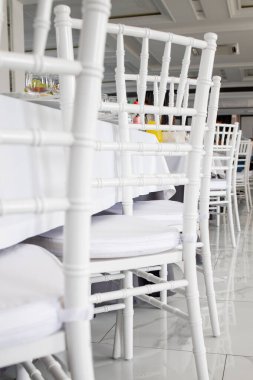 Restorandaki masalarda beyaz sandalyeler, beyaz masa örtüleri..