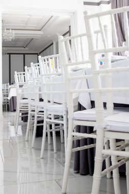 Restorandaki masalarda beyaz sandalyeler, beyaz masa örtüleri..