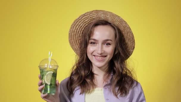 Überraschte Frau Trinken Mojito Cocktail Aus Plastikbecher Über Gelbem Studiohintergrund — Stockvideo