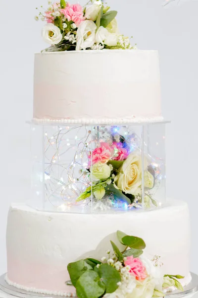 Tiered cake for wedding or birthday. Beautiful white and pink festive cake decorated with flowers.