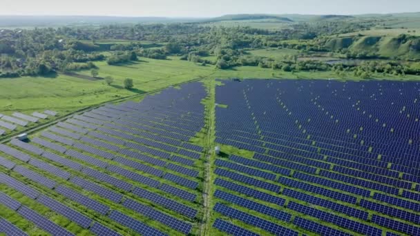 晴れた日に川の近くのグリーンフィールドの太陽光発電所の空中ビュー 太陽農場を飛び越える 太陽光パネルは生産のために列に立つ — ストック動画