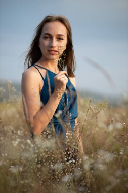 Çiçek açan bir tarlanın ortasında esmer bir kadın. Polen ve çiçek alerjisi