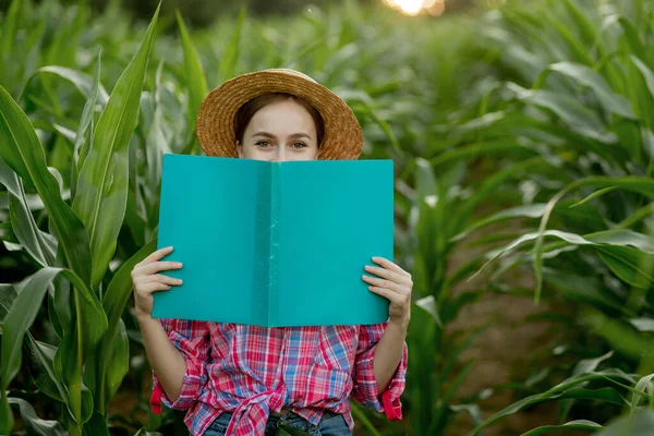 Farmer with a folder stands in a corn field and checks the growth of vegetables. Agriculture - food production, harvest concept.