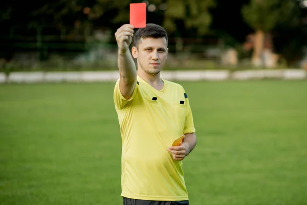 Referee showing a red card to a displeased football or soccer player while gaming. Concept of sport, rules violation, controversial issues, obstacles overcoming