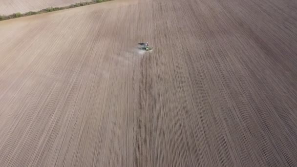 Zicht vanuit de lucht op trekker met eggen systeem ploegen grond op landbouwgrond, pijler van stofpaden achter, voorbereiding van de bodem voor het planten van nieuwe gewassen, landbouw concept, bovenaanzicht — Stockvideo