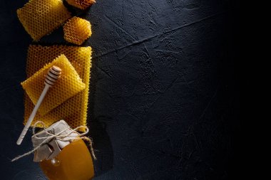 Kavanozda bal ve bal peteği. Siyah tahta bir arka planda. Metin için boş alan. Üst görünüm